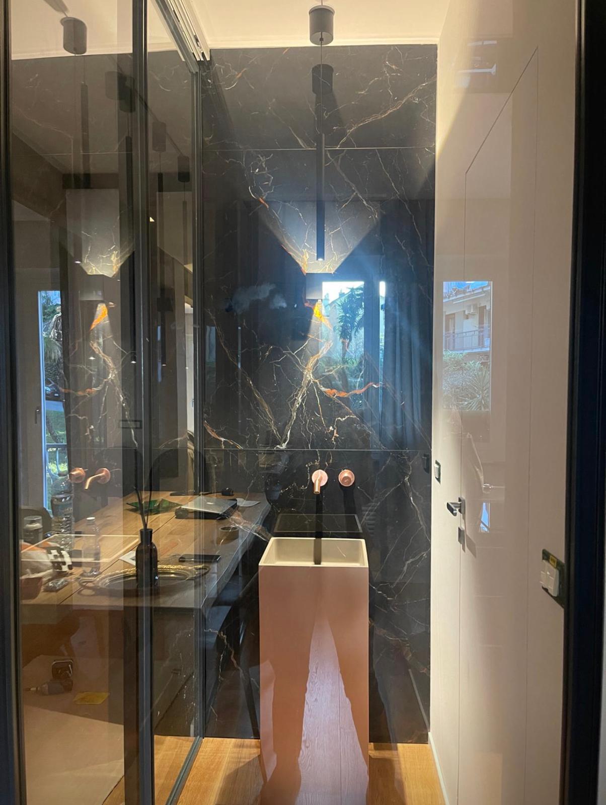 Bagno con marmo nero venato oro e lavabo scultoreo rosa