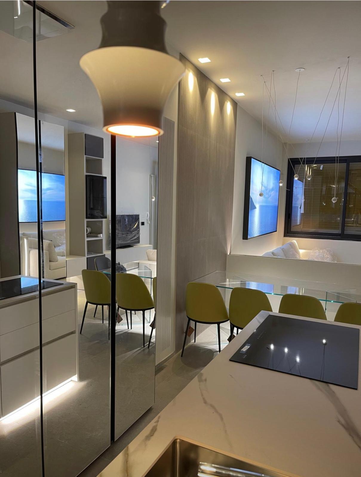 Cucina con piano in marmo, colonna a specchio e sedute senape