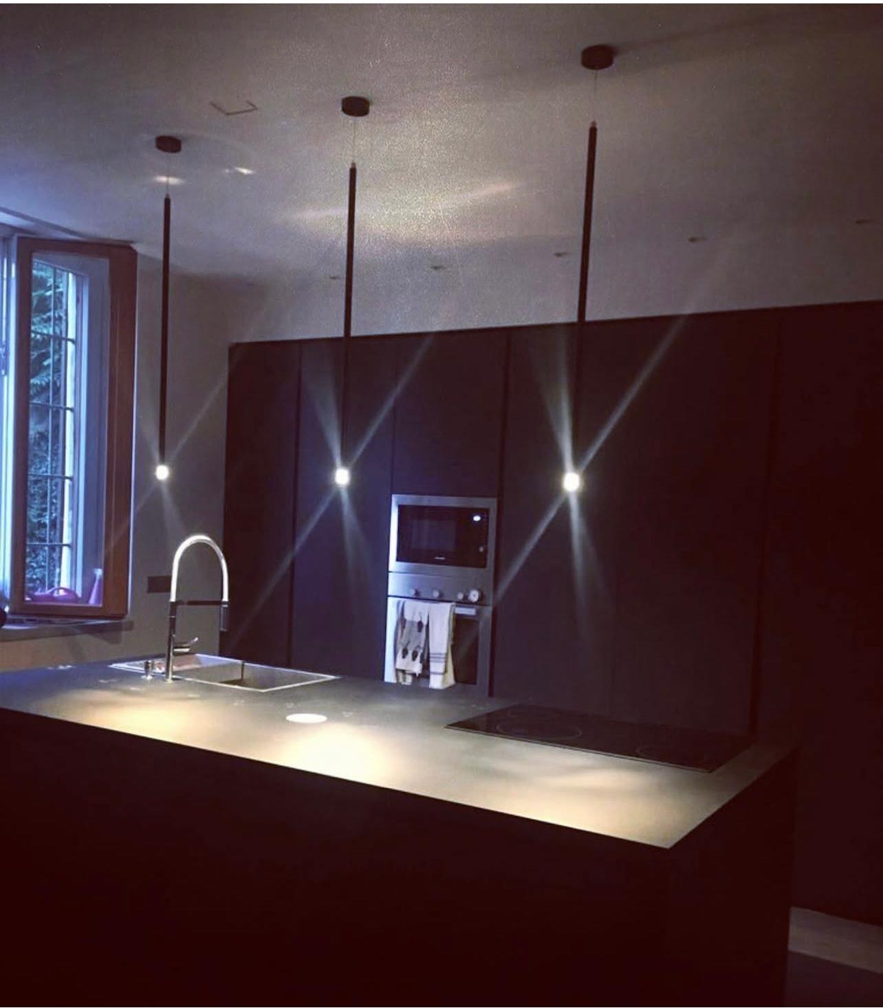 Cucina scura con pensili a tutta altezza e lampade a sospensione