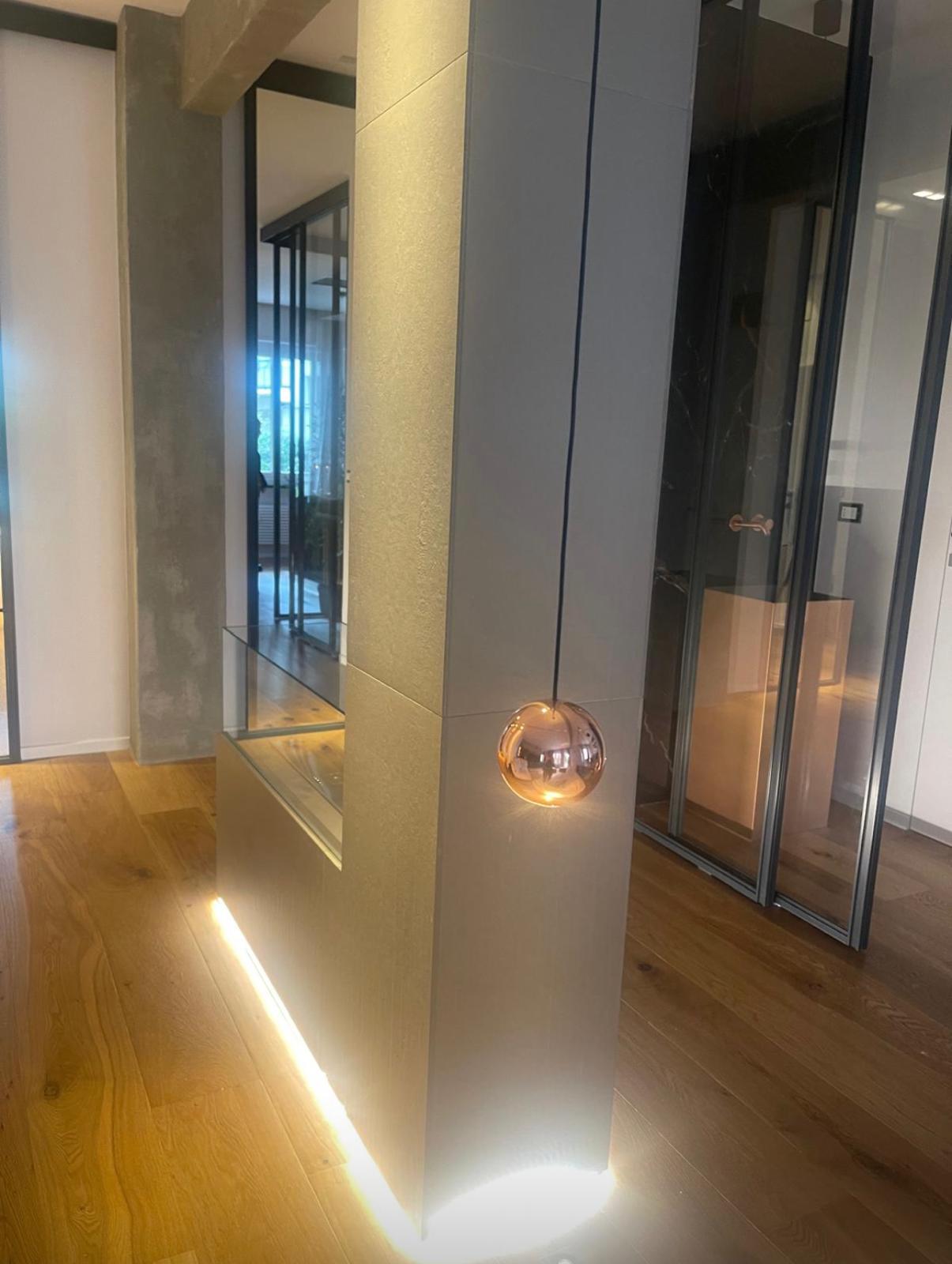 Dettaglio pilastro con lampada a sfera sospesa color rame