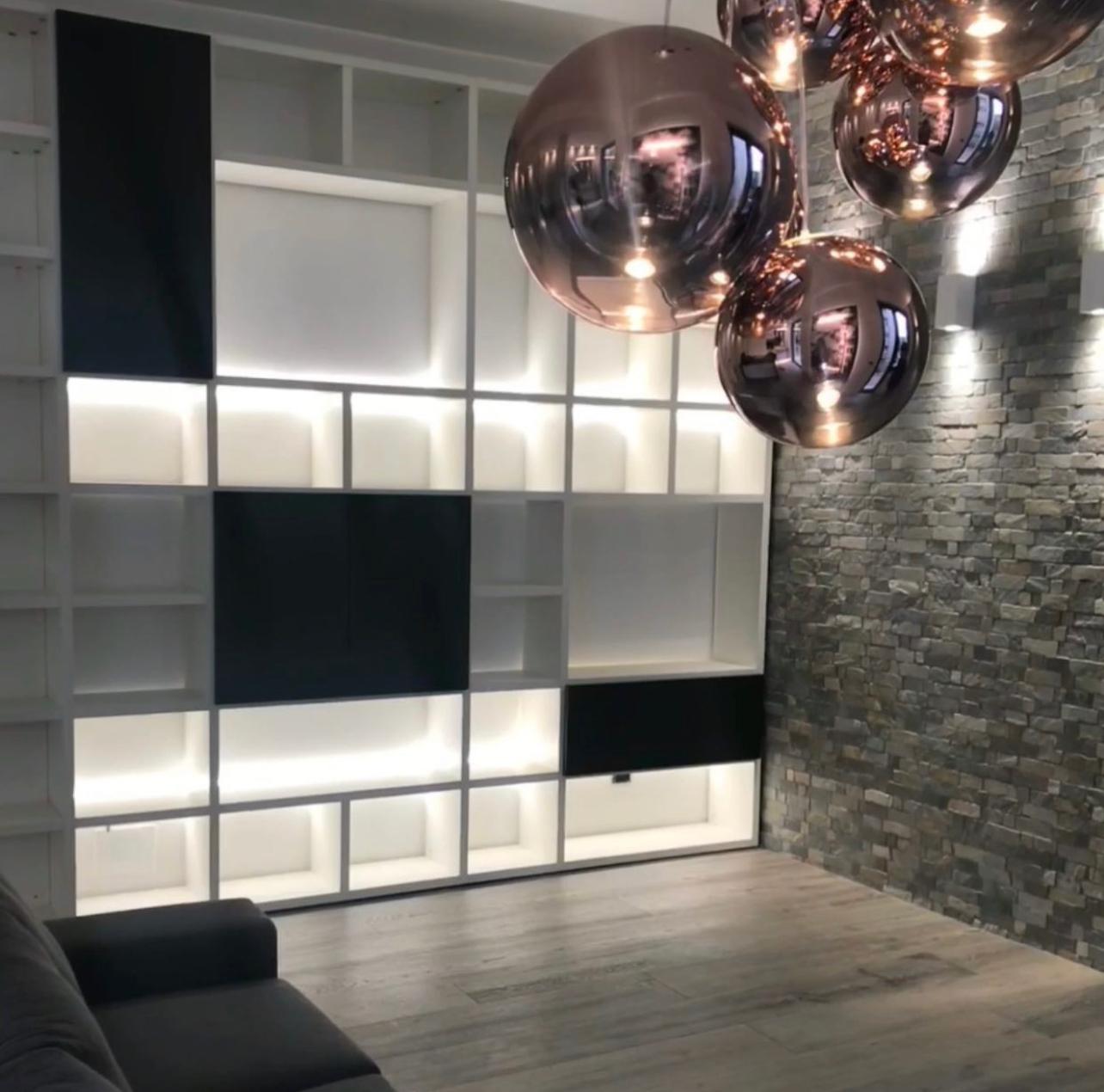 Parete libreria retroilluminata con lampade a sfera in rame