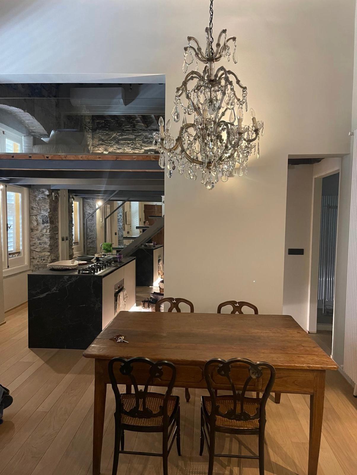 Sala da pranzo con lampadario a gocce e cucina a vista sul soppalco